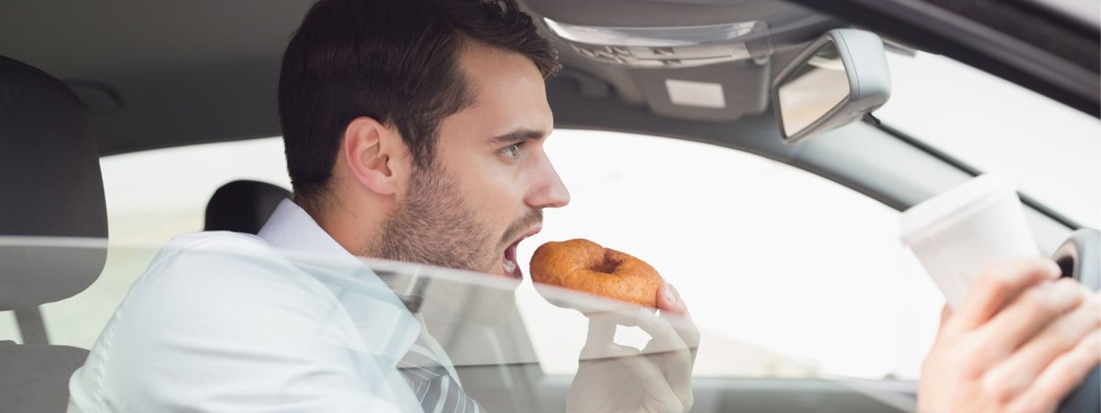 A man is eating food in a car